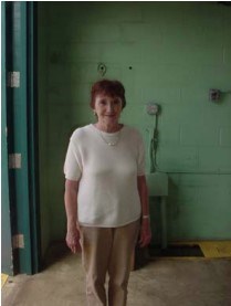 an older women poses in front of a green wall