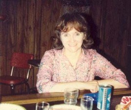 a woman in a floral blouse sits at a bar