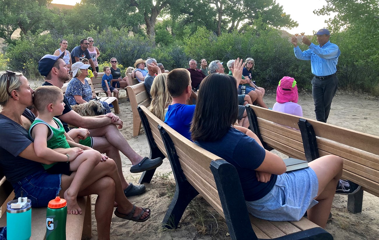 Evening ranger program at the Green River Campground Ezparza-Limón leading an evening ranger program at the Green River Campground. Standing, he holds up two models of butterflies in front of a crowd of seated spectators.