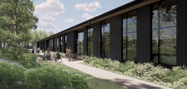 Artistic rendering of the side of the maintenance building. Glass windows line the side of the building, looking over chairs and tables.