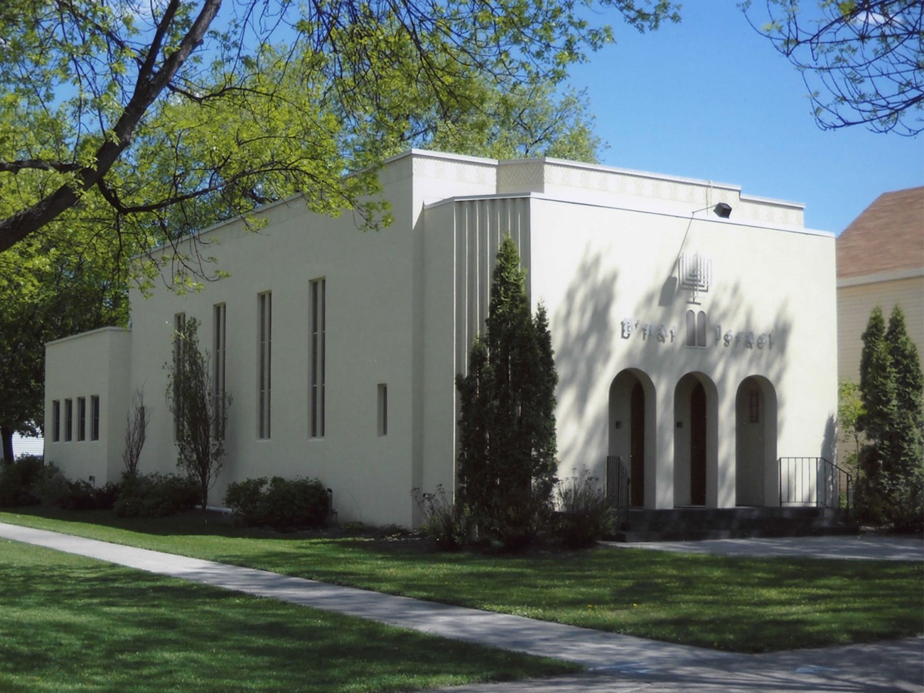 B'nai Israel Synagogue A light-colored building with three arched openings on the front and tall, narrow windows on the side. The words "B'nai Israel" are above the front entrance.