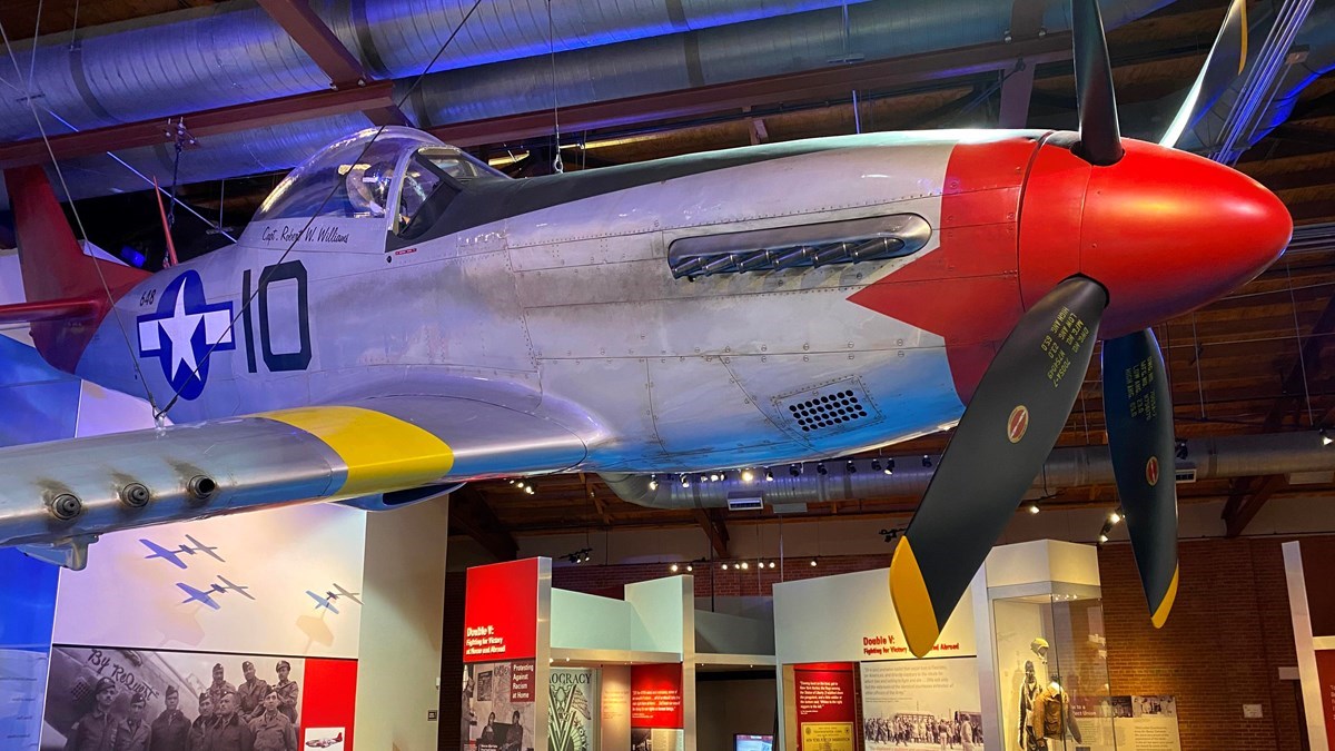 A replica P-51 Mustang "Red Tail," it is hung on the ceiling on display at a museum