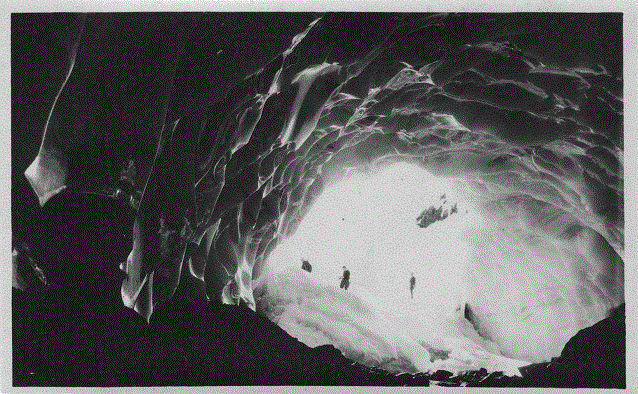 black and white photo from inside an ice cave looking out at a group of people