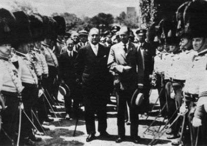 Man walking with cane on arm of another man in between groups of men on either side