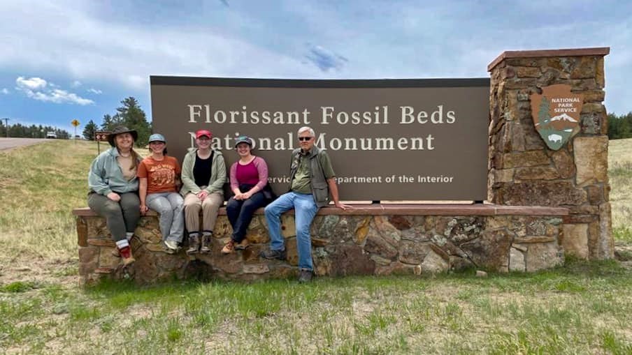 photo of 5 people sitting on the Florissant Fossil Beds entrance sign.