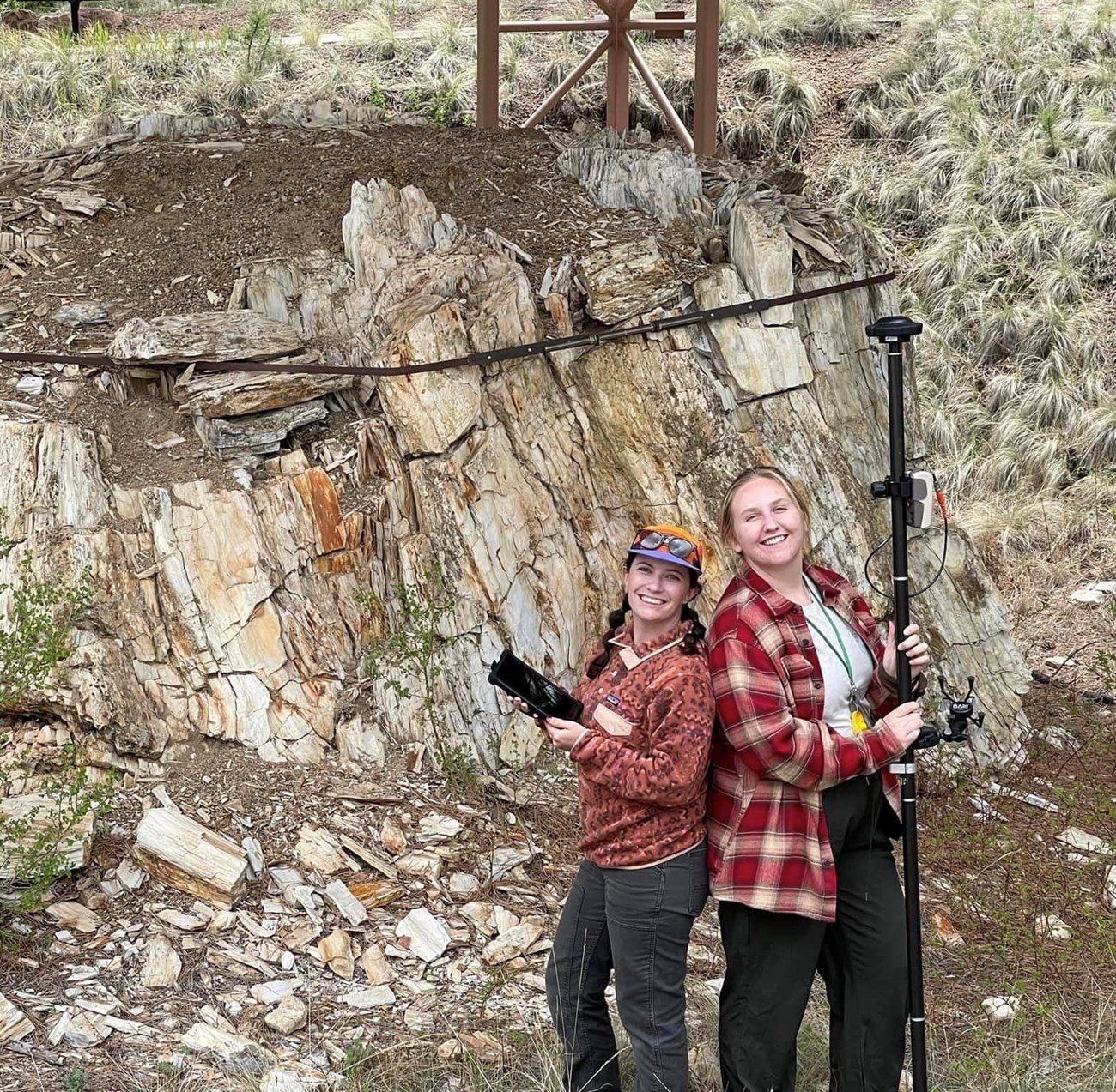 Photo of 2 people standing in front of a large fossil stump.