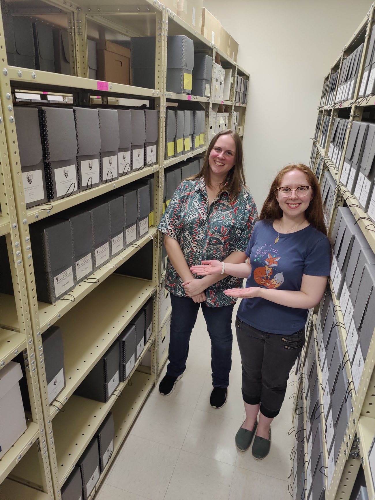 Photo of two people standing between storage shelves.