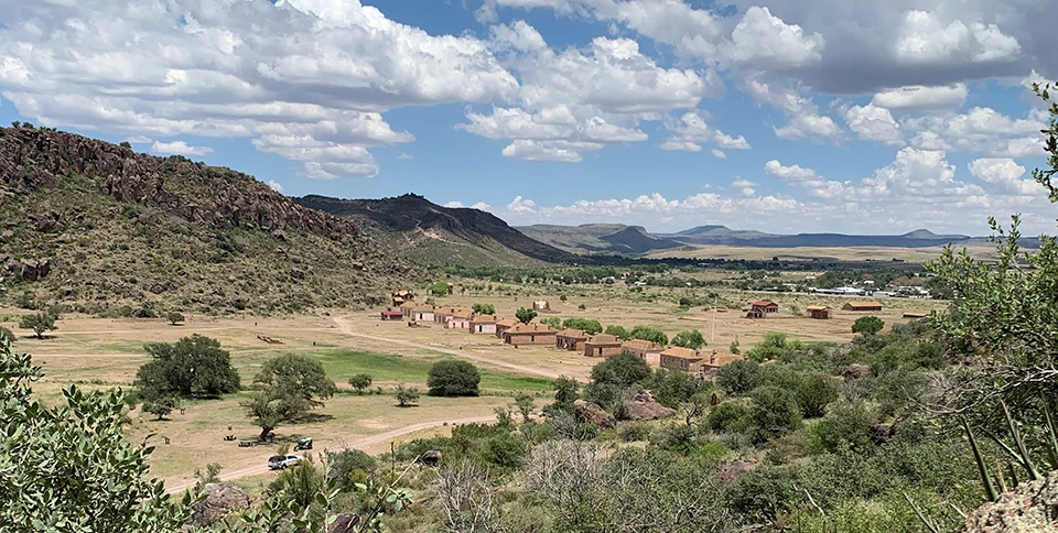 Fort Davis National Historic Site A landscape view of Fort Davis buildings, grassland, and rocky hills under fluffy clouds.