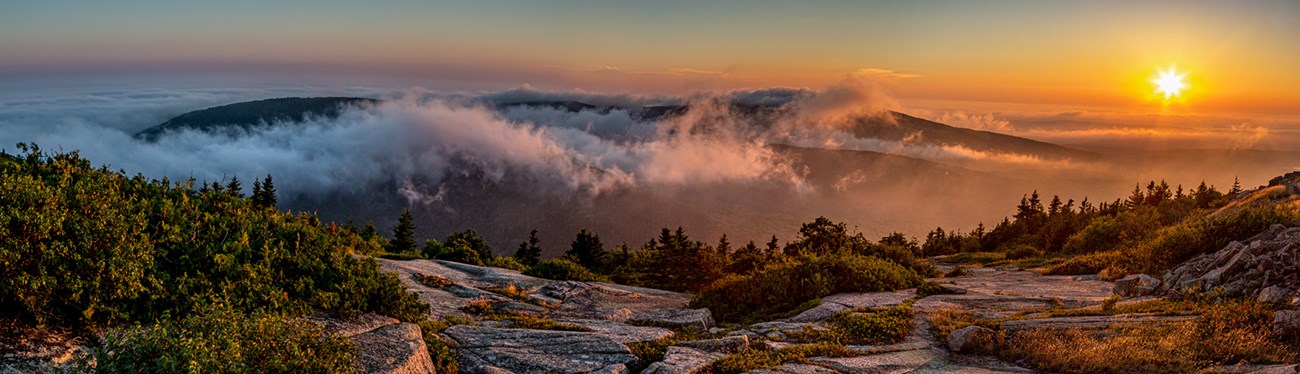 Early morning landscape image of mountains with fog and rising sun