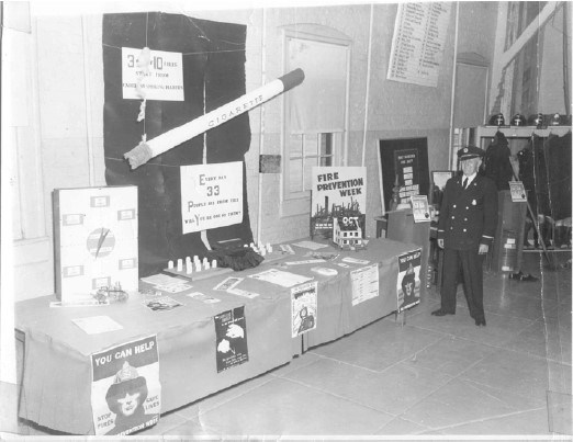 a man stands next to an informational fire prevention week table