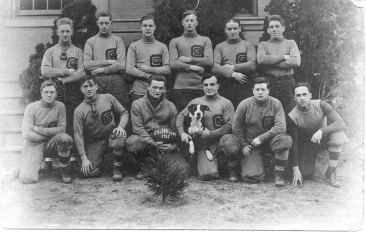 12 men in sports jerseys pose with a dog and football