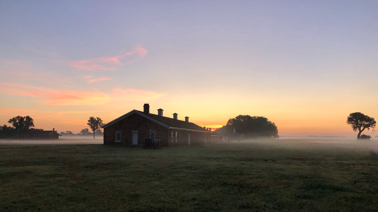 Standstone building, Fort Larned A one-floor, sandstone building with multiple chimneys stands out amidst the morning dew.