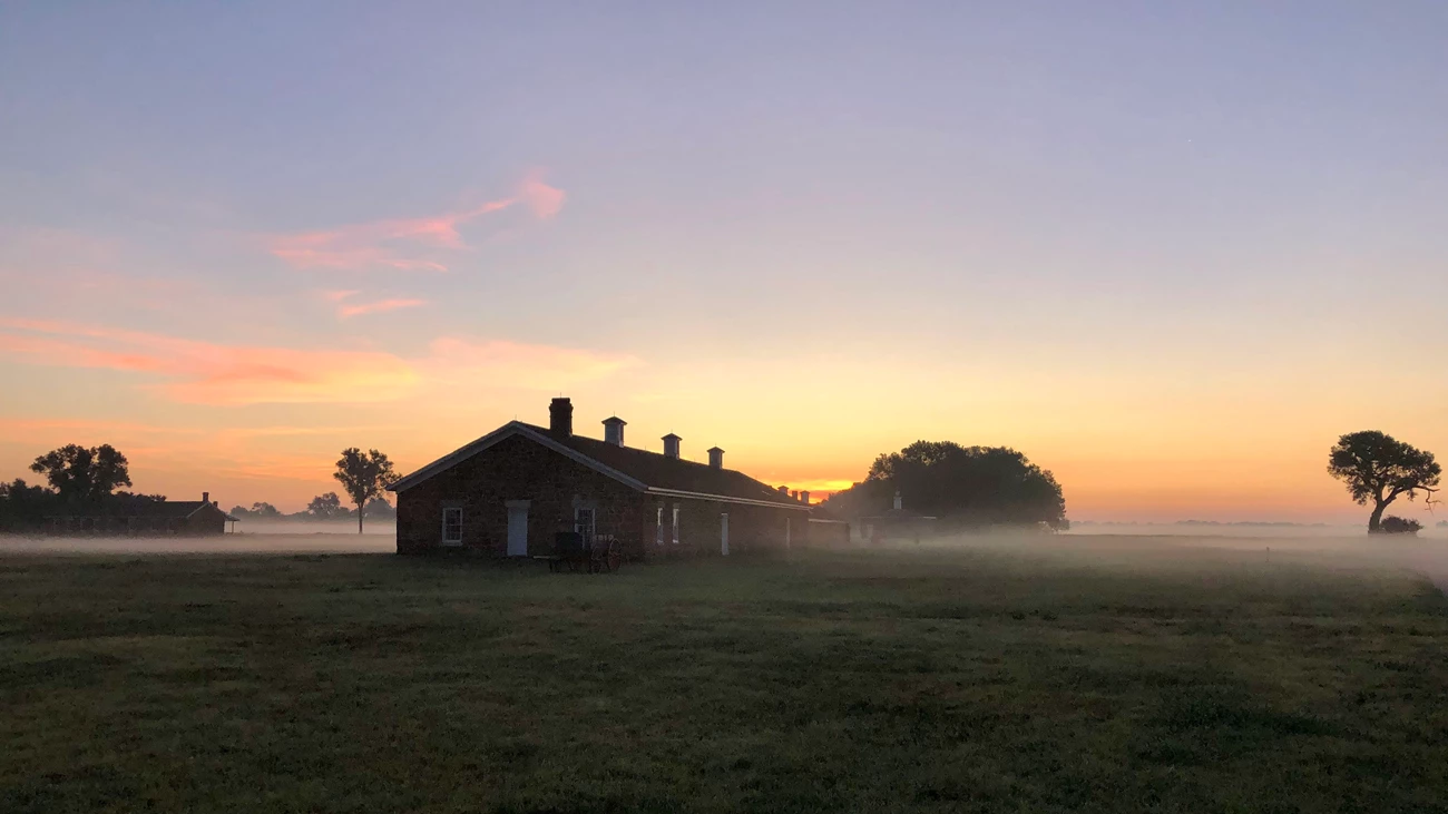 Standstone building, Fort Larned A one-floor, sandstone building with multiple chimneys stands out amidst the morning dew.