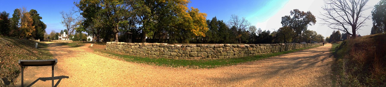 A stone wall along a gravel road. A stone wall along a gravel road.