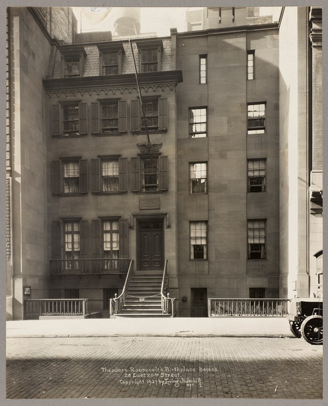 A black-and-white photo of the facade of Theodore Roosevelt’s recreated birthplace. 