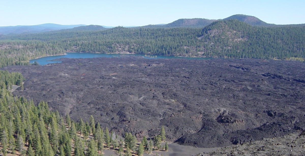 photo of a large lava field surrounded by forested hills