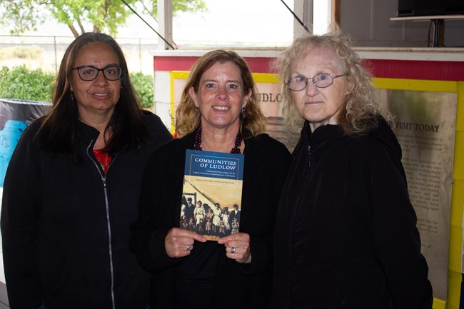 Fawn-Amber, Karin, and Mary Elaine Three women; center woman holds a book cover