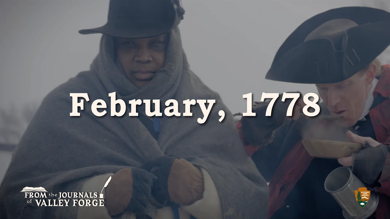 February 1778 From the Journals of Valley Forge A man stands wrapped in a blanket on the left and on the right another man spoons a steaming liquid into his mouth.