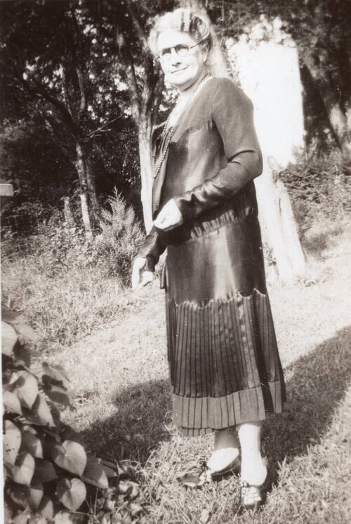 Black and white photo of a woman standing in a garden Wiki