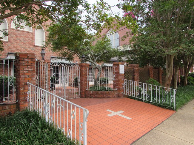 Brown brick Church behind a white metal fence