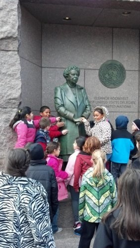 A group of students gathered around the bronze statue of Eleanor Roosevelt in the FDR Memorial