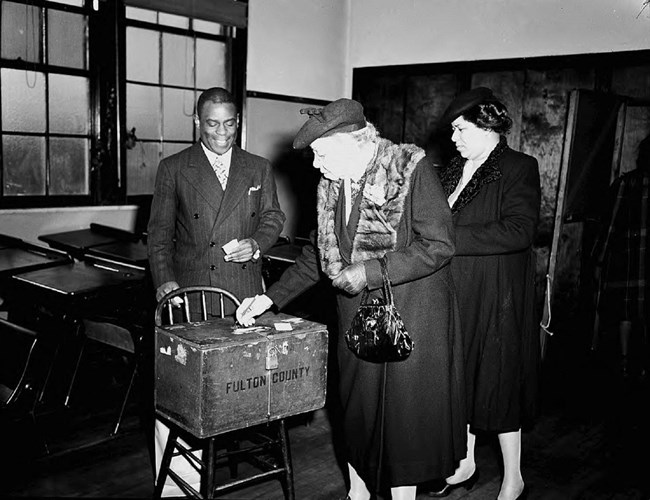 Two women putting ballots in a ballot box