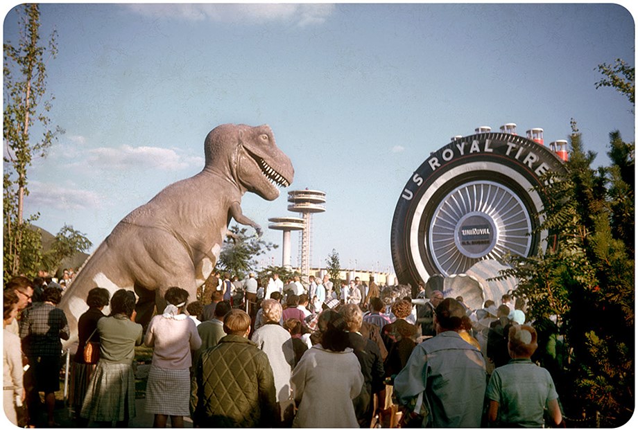 Large crown in front of T-Rex Statue. Larger than life U.S. Royal Tires on right, observation towers in the background.