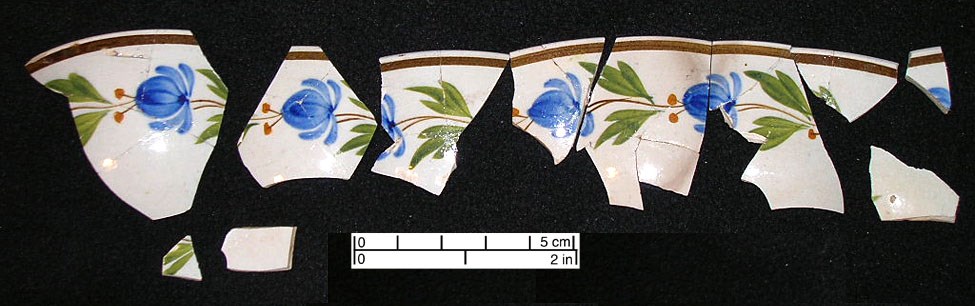 Fig5.05 pieces of a hand painted pearlware teacup with a polychrome floral design in blue, green, and yellow, arranged in a line.
