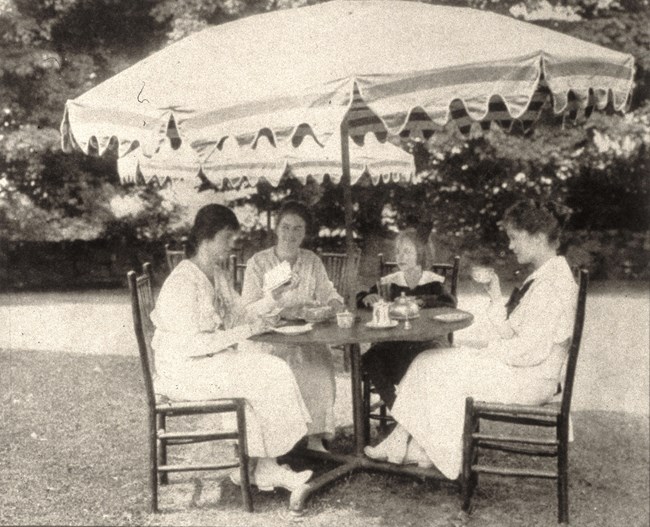 Tabby Cat Tea House Four women sit at a table under a large umbrella drinking tea.