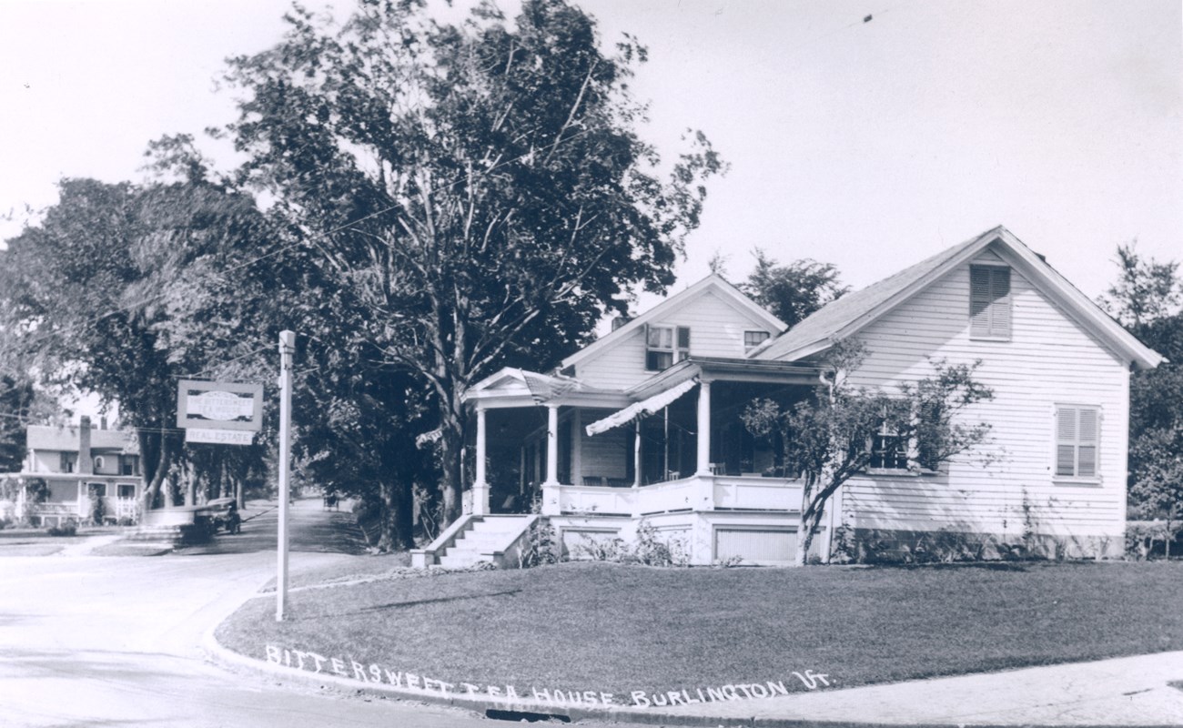 White house with a covered porch on a street corner with a sign reading Bittersweet Tea House.