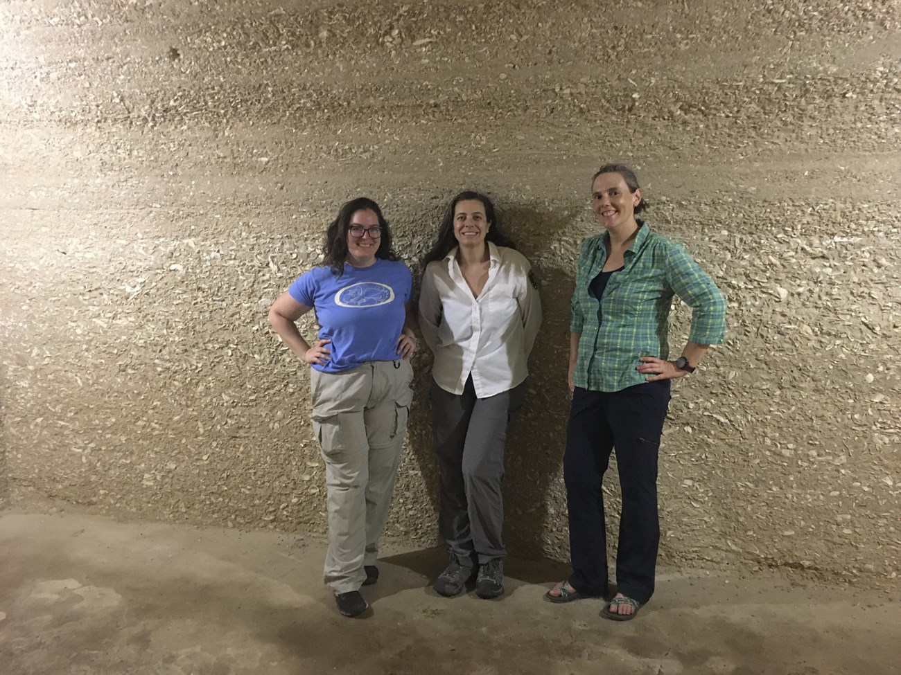 Photo of 3 people standing in front of bluff with fossil shell beds.