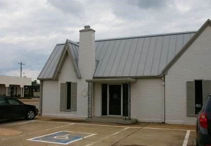 Gray brick building with darker gray metal roof.