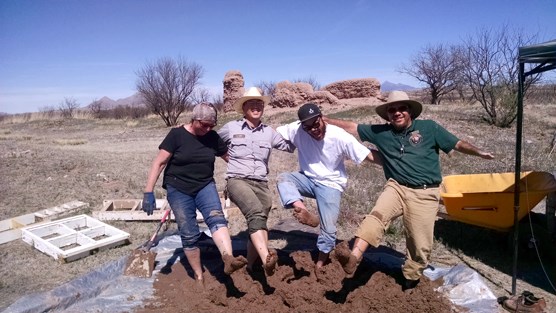 lt= group of people smiling with bare feet in mud pile