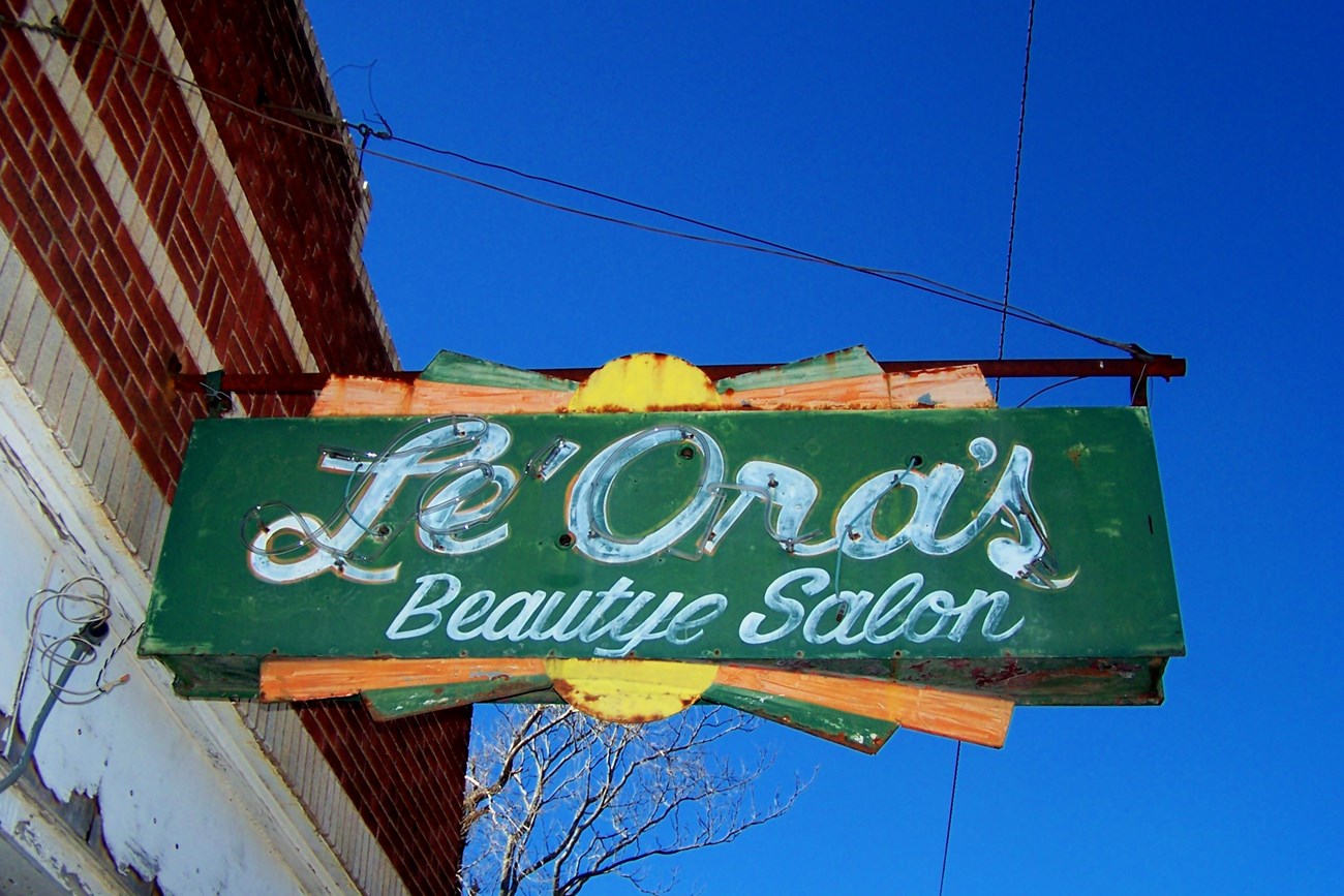 LeOras Beautye Salon Weathered neon green rectangular sign with white script text reading Le'Ora's Beautye Salon.
