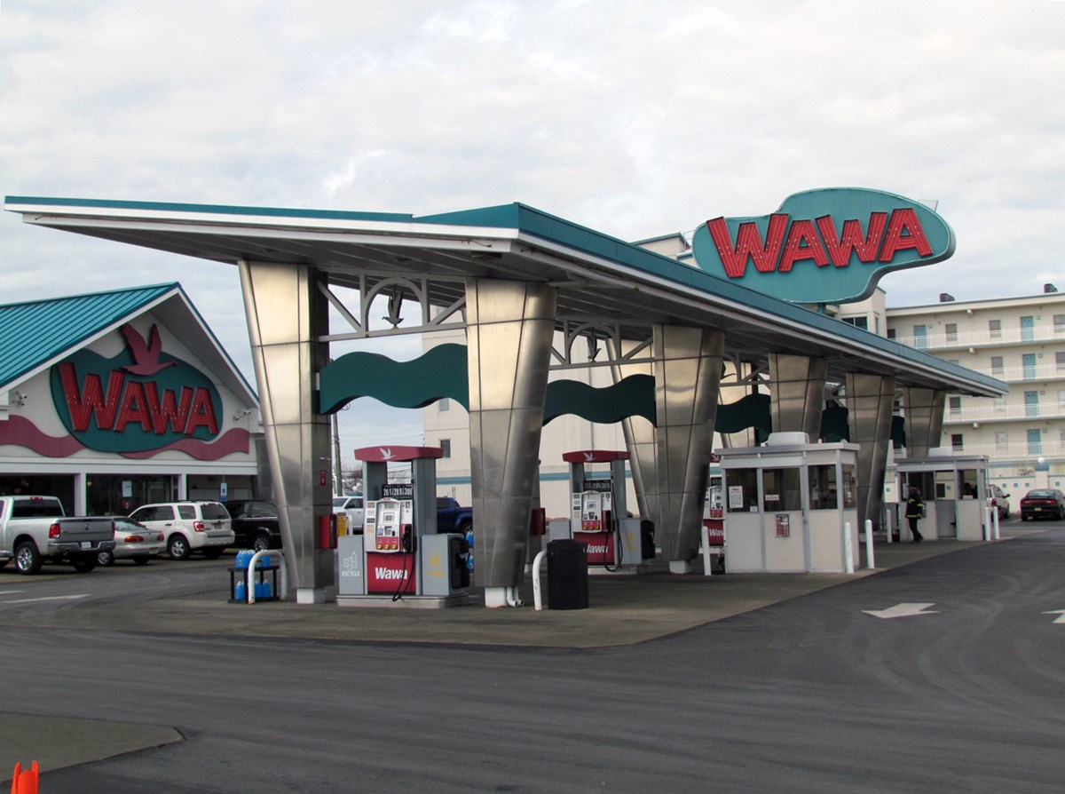 Modern gas station with turquoise trim and marron text on sign reads WAWA.