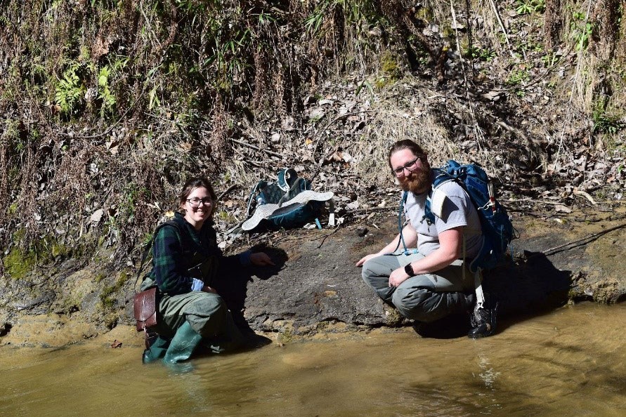 photo people kneeling in shallow water and the base of a steep slope