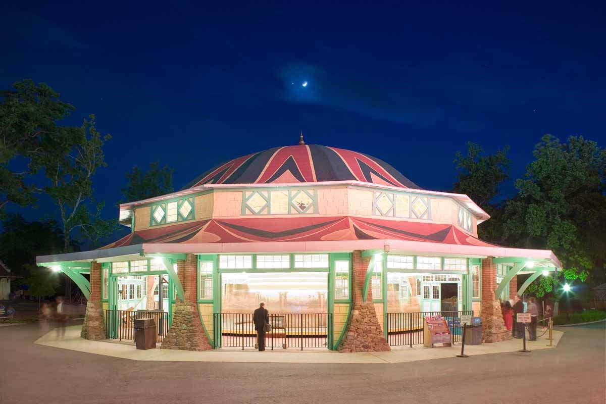 Lit up at night - Octagonal building with green, red, and pink roof and green awing supports.
