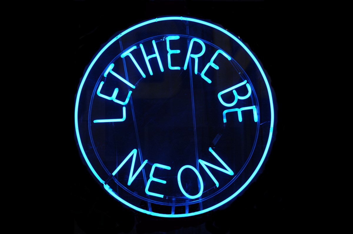 Blue neon circle with inside blue neon text reading Let there be neon.