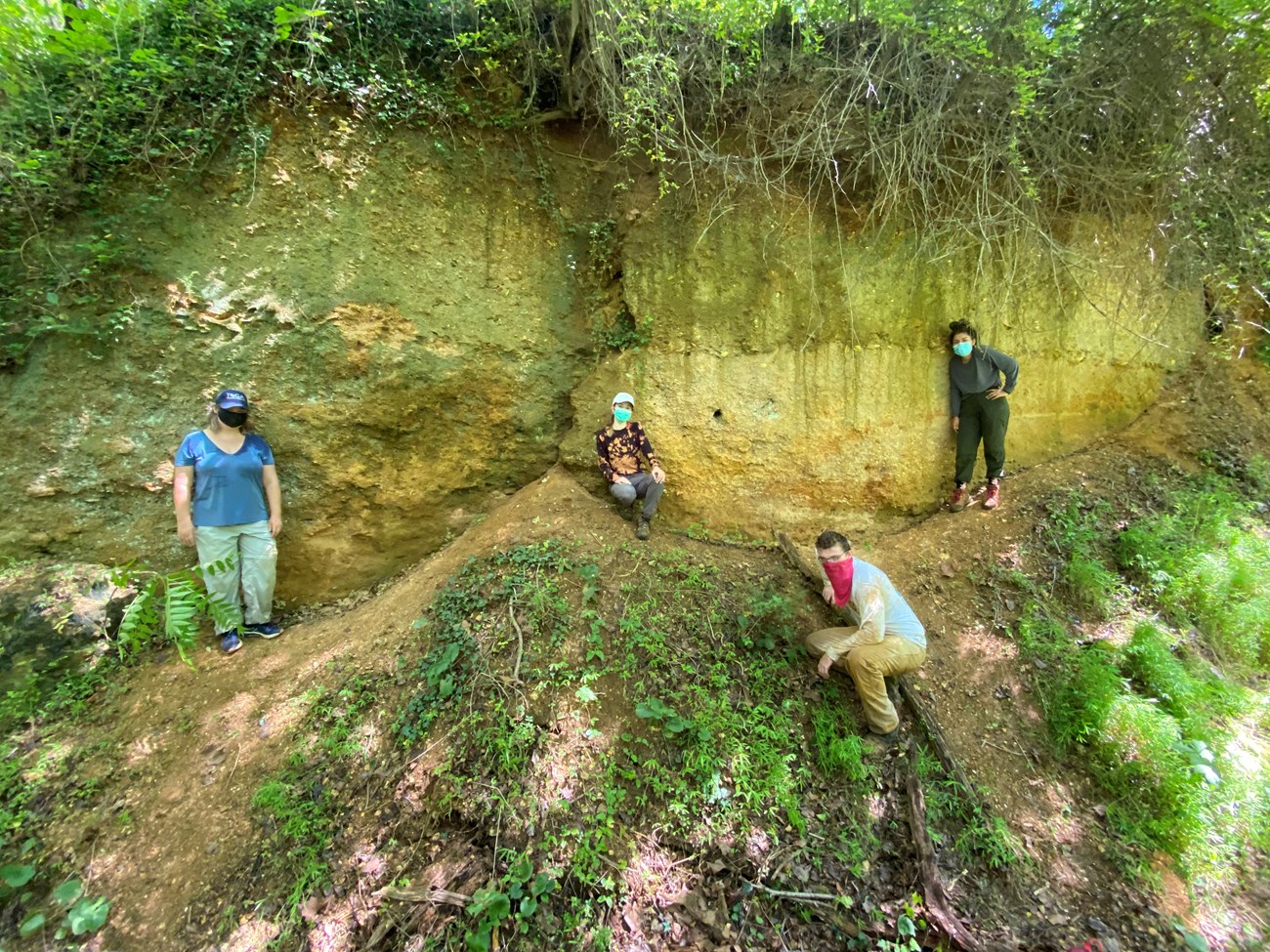 four people standing at the base of a bluff