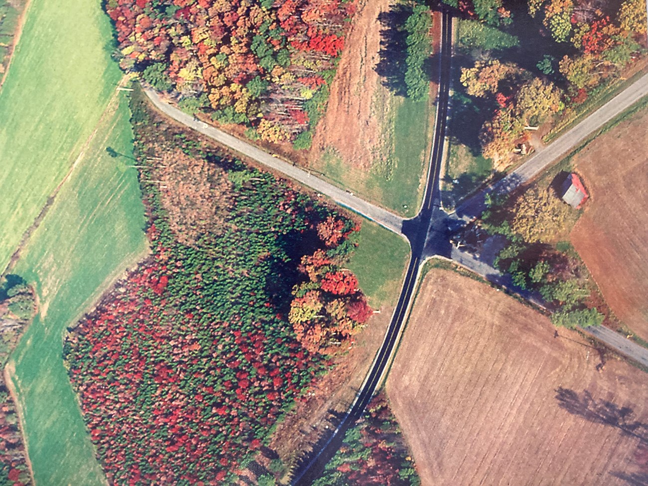 Aerial View in fall of five roads coming together. Surrounding areas is fields covered with trees.