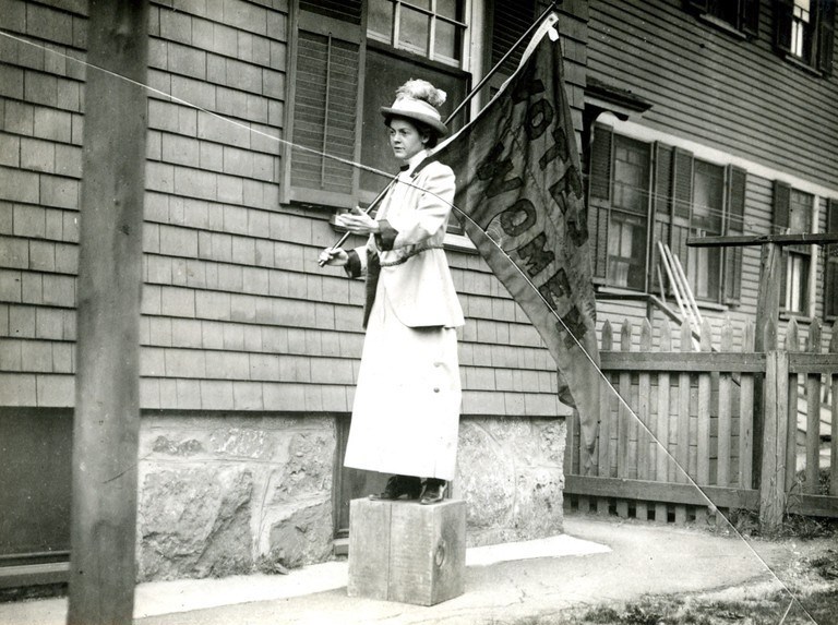 FlorenceLuscomb-SL Suffragist Florence Luscomb stands on a soap box with a votes for women flag