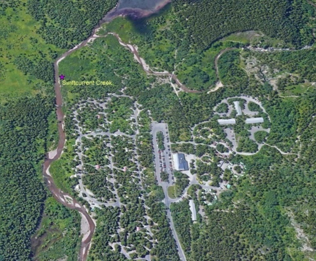 Aerial photo showing roads, parking and buildings next to a stream.