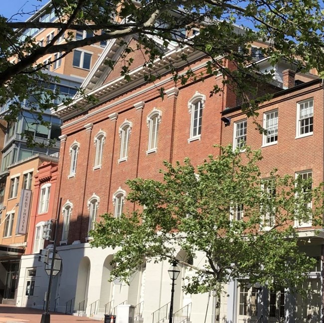 The brick facade of Ford's Theatre on empty city street on a sunny day.