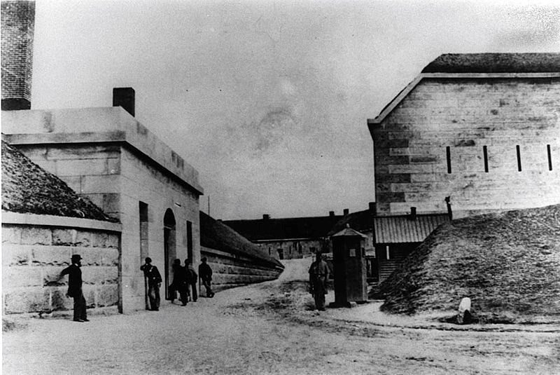 Black and white image of the Guardhouse at Fort Warren. A group of six are standing around.