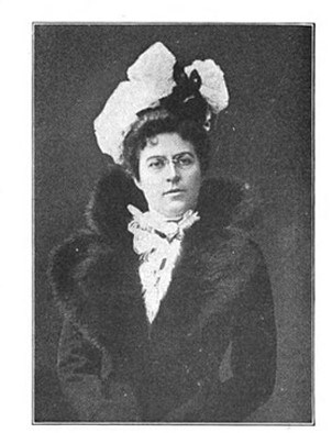 black and white photograph of woman wearing elaborate hat and jacket with large fur collar