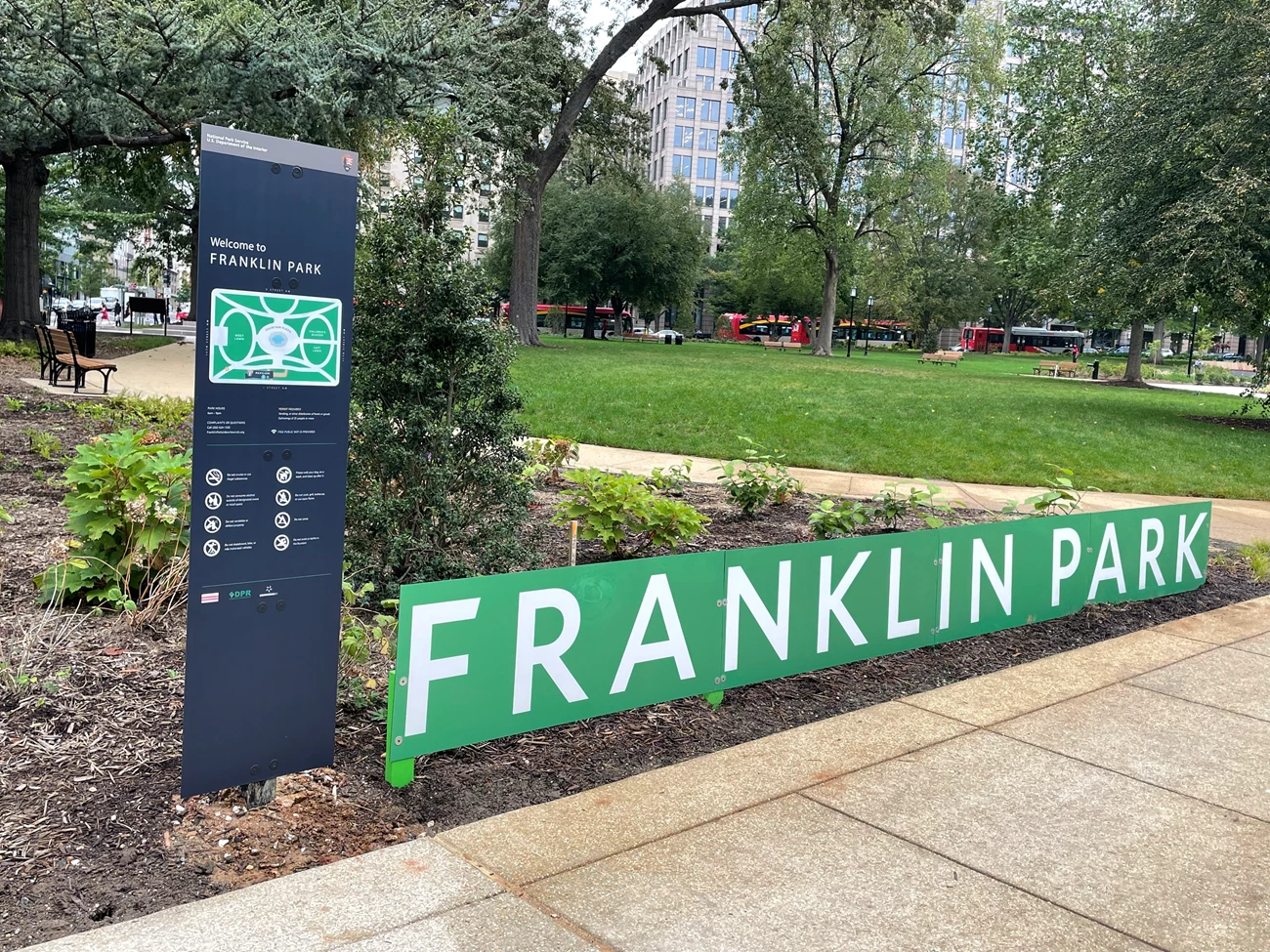 Franklin_NPS Franklin Park Sign with green grass and trees and busses in the background.