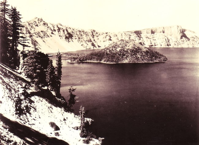 Black and white photo an island in a lake surrounded by rock formations.