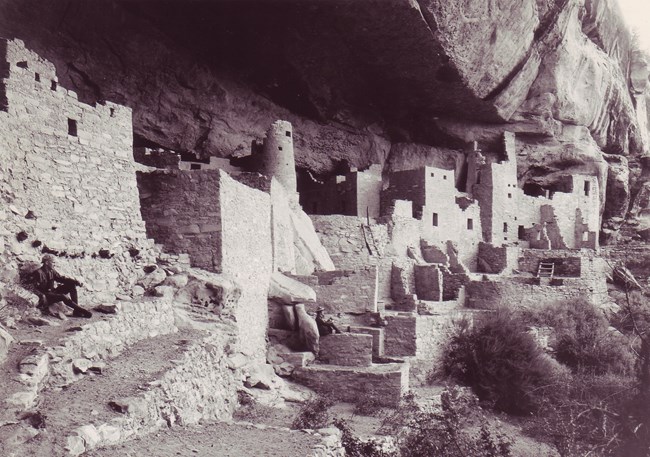 Black and white photo of Cliff Palace with rangers