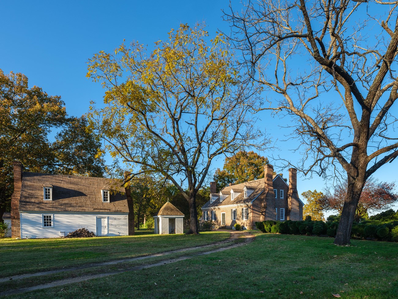 side view of the white wooden Colonial Revival Kitchen and brick Memorial House Museum