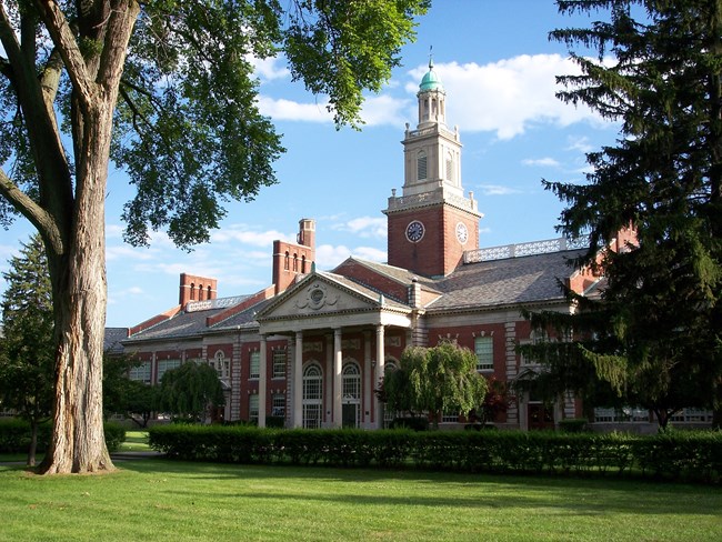 Large brick building with greco-roman columns and spire on top.